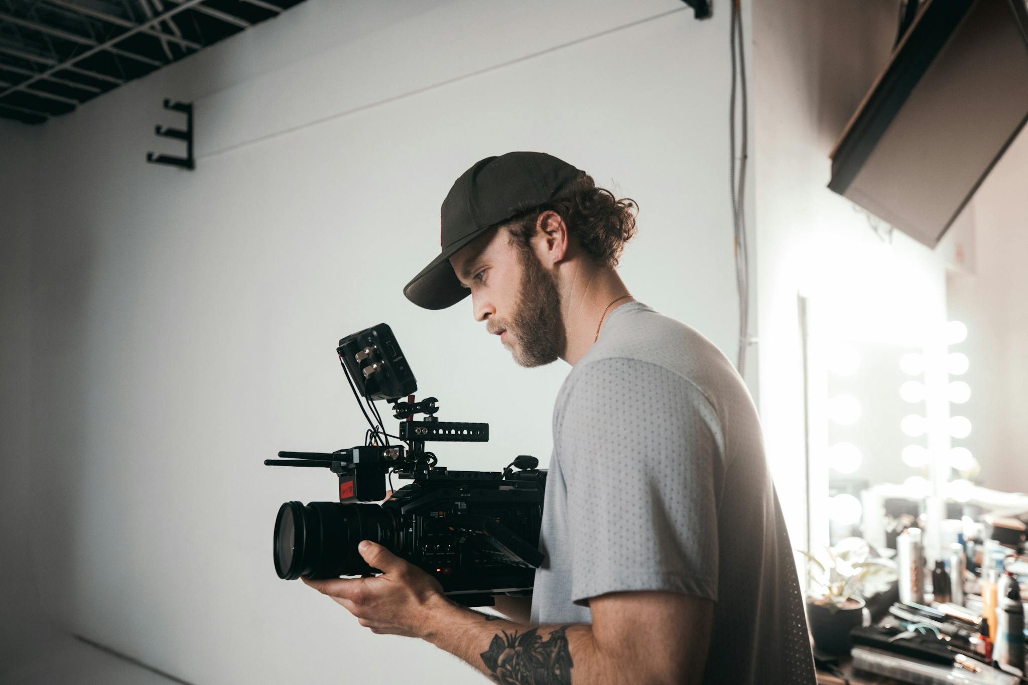 Caucasian man filming on set using professional camera equipment in a studio.